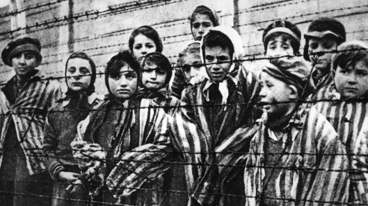 Children behind a barbed wire fence at the Nazi concentration camp at Auschwitz in southern Poland.   (Photo by Keystone/Getty Images)